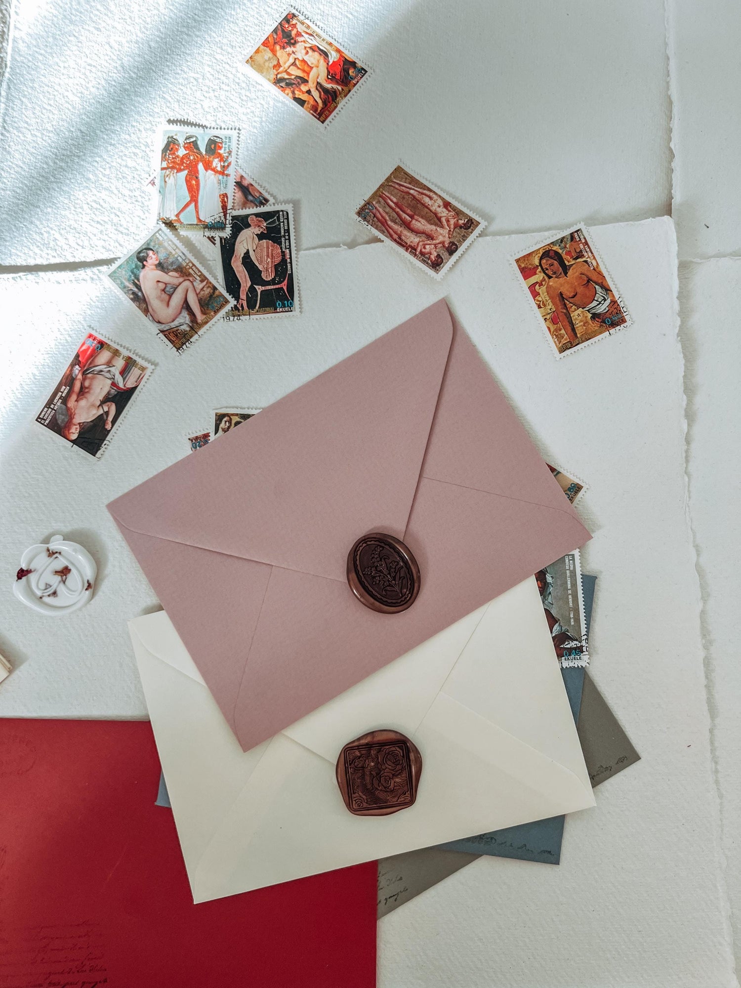 Pink envelope with wax seal surrounded by vintage-style cards on a textured surface